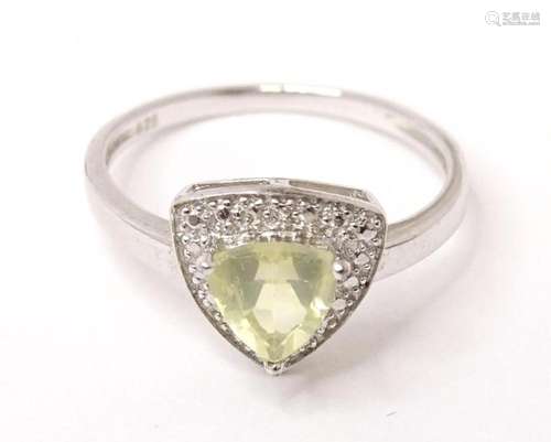 A silver ring set with triangular pale green stone in triang...