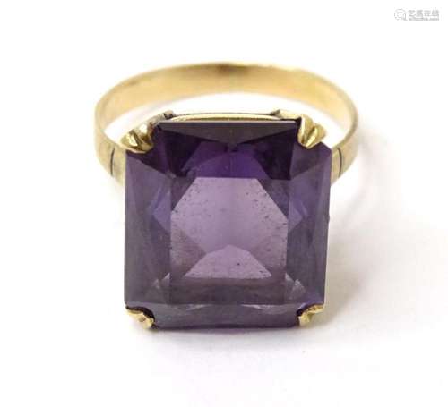 A yellow metal ring set with central purple stone. Ring size...