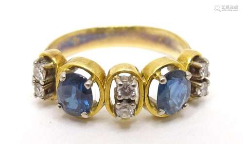 An 18ct gold ring set with diamonds and blue stones. Ring si...