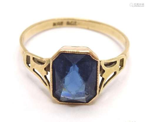 A 9ct gold ring set with facet cut blue glass stone in an Ar...