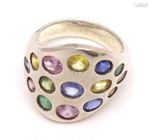 A white metal ring set with sapphires, pink sapphires, emera...