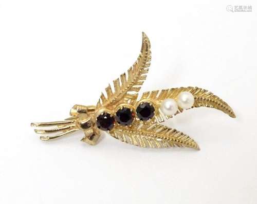 A 9ct gold brooch of foliate sprig form set with garnets and...