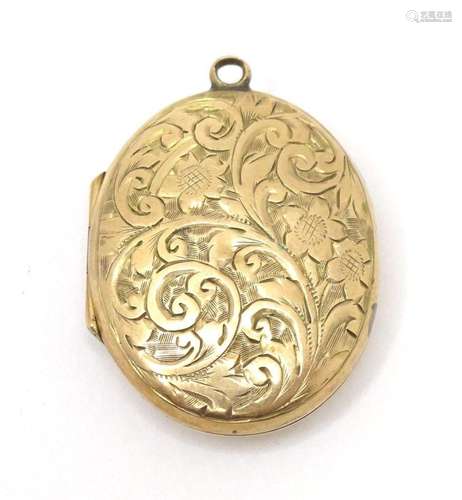 A 9ct gold locket of oval form with engraved decoration, hal...