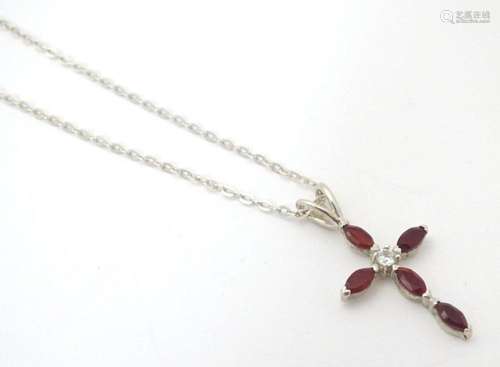 A silver pendant of cross form set with red and white stones...