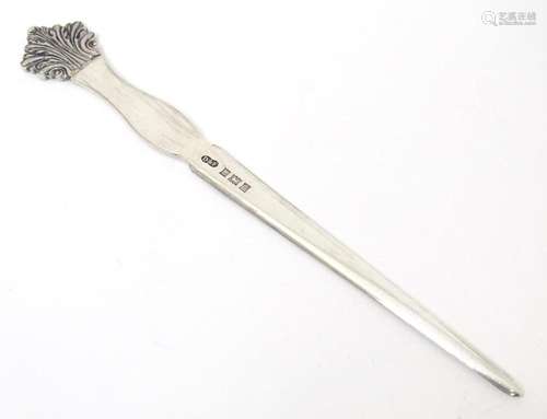 A silver letter opener the handle surmounted by foliate deco...