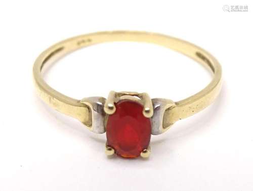 A yellow metal ring set with central red stone. Ring size ap...