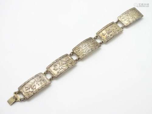 A silver bracelet set with various panels with floral, butte...