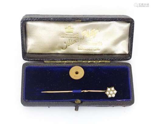 A 15ct gold and yellow metal stick pin surmounted by seed pe...