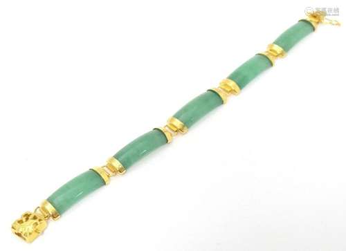 A jade coloured hardstone bracelet with yellow metal mounts....