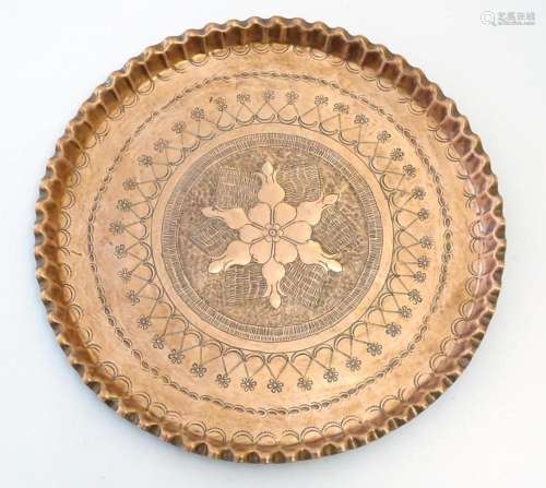 An early 20thC copper charger with scalloped edge, central A...