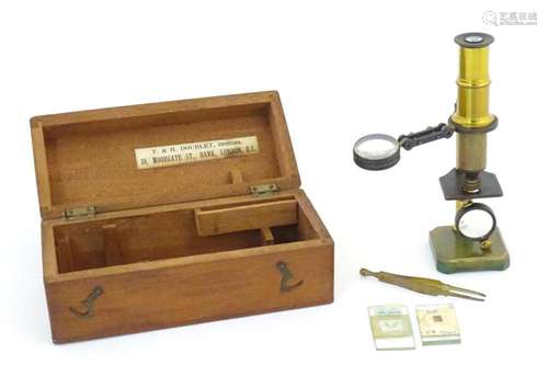 A 20thC brass monocular microscope within a fitted case with...