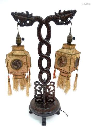 An Oriental carved table lamp of twin branch form with drago...