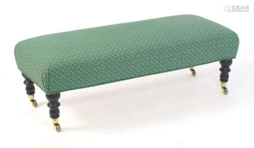 A long upholstered stool raised on four turned tapering legs...