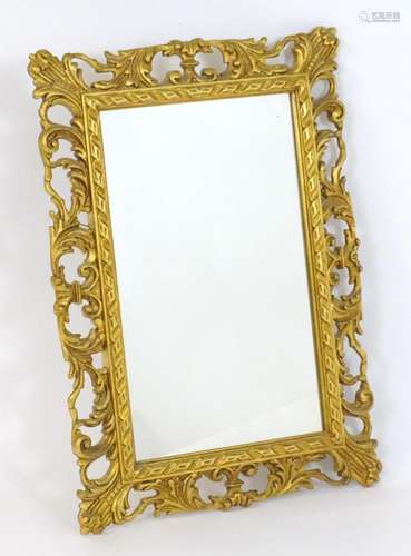 A 20thC giltwood mirror with a pierced floral carved frame. ...