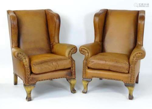 A pair of wingback armchairs upholstered with studded leathe...