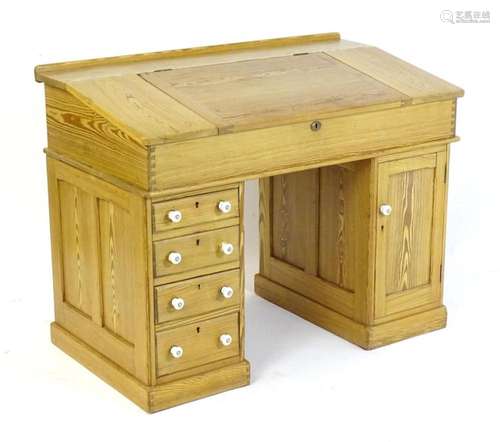 A 20thC pitch pine clerks desk, having a hinged lid opening ...