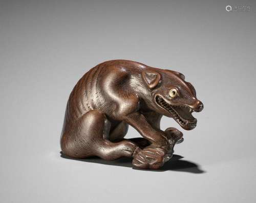 † A FINE WOOD NETSUKE OF A WOLF WITH HAUNCH OF VENISON