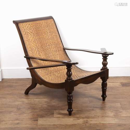 Plantation chair having a stained wood frame and woven ratta...
