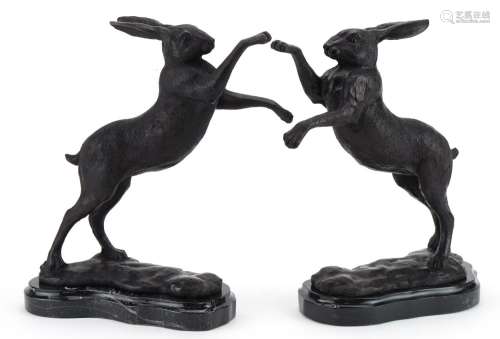 Pair of patinated bronze boxing hares raised on marble bases...
