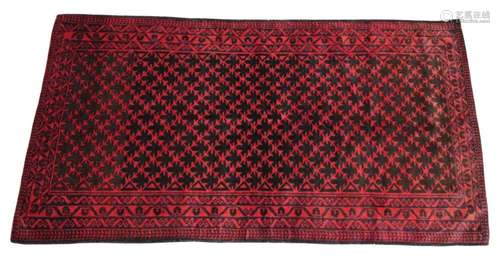 An Afghan Belouch wool rug, in deep red and blue colourways,...