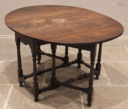 An 18th century oak drop leaf dining table, the oval plank t...