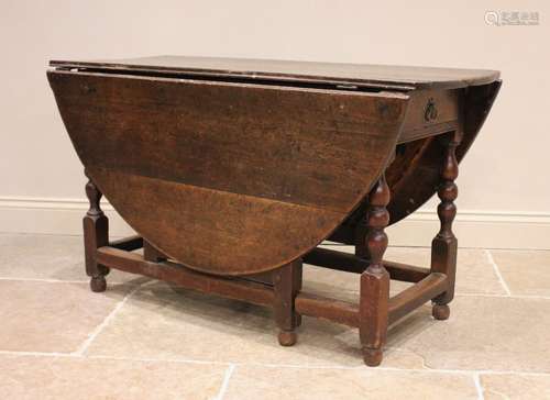 An 18th century oak drop leaf dining table, the oval plank t...