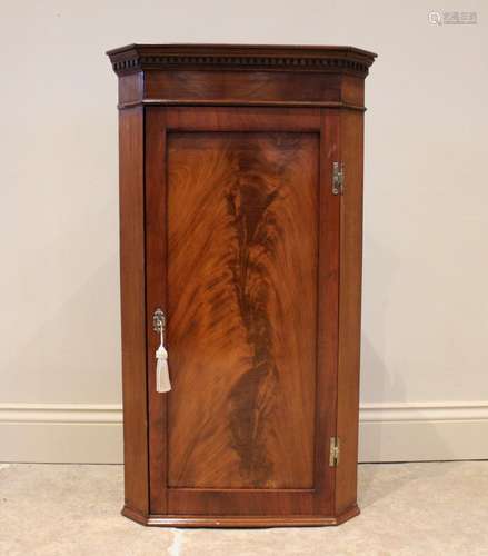 A George III and later mahogany corner cupboard, the hinged ...