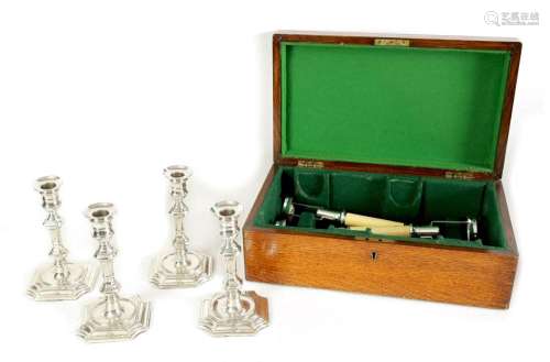 A GEORGE V OAK CASED SET OF FOUR GEORGE I STYLE SILVER CANDL...