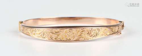 An Edwardian 9ct gold oval hinged bangle, the front with flo...