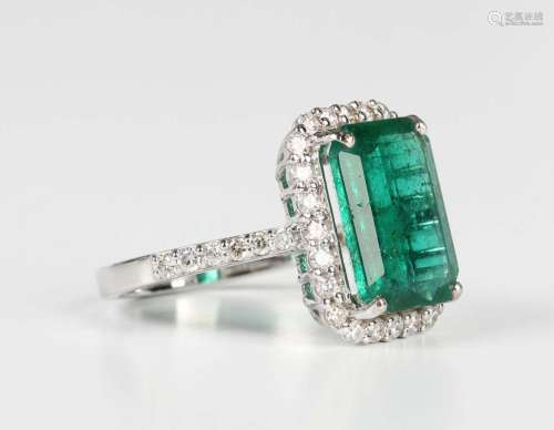 A white gold, emerald and diamond cluster ring, claw set wit...