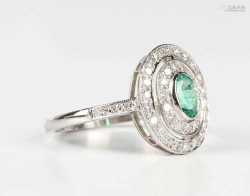 A platinum, emerald and diamond oval cluster ring, collet se...