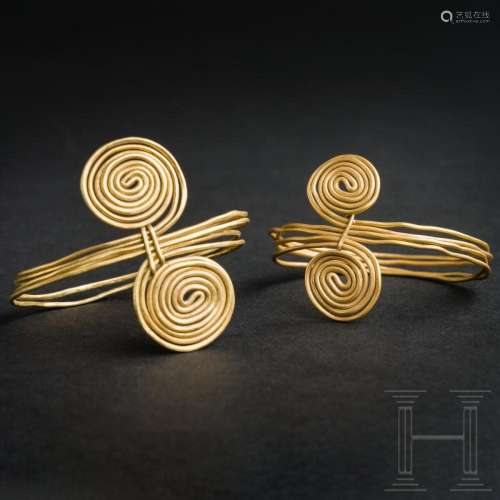A pair of gold wire rings with four loops and spiral ends, l...