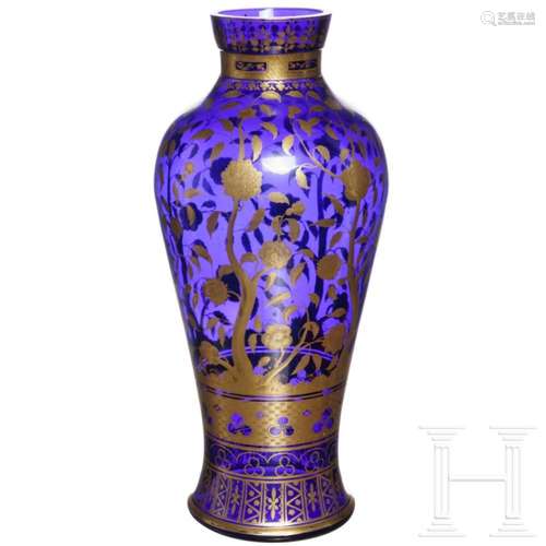 A large cobalt-blue glass vase with gilded floral decor, pro...