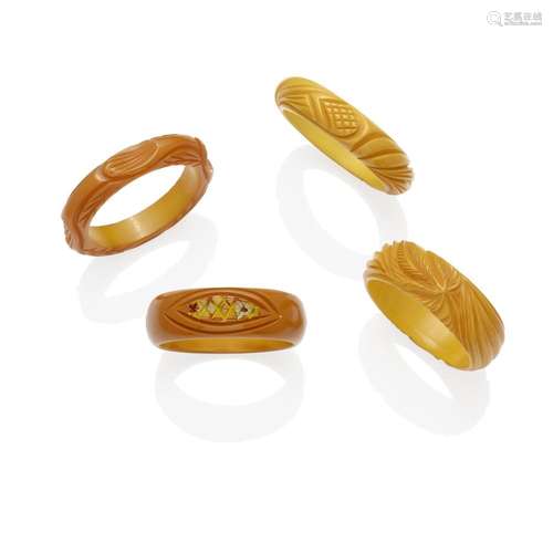 FOUR CARVED BAKELITE BANGLES one with some painting, in foli...