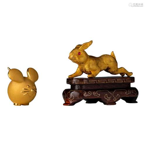 Two gold ornaments, one depicting a rabbit and the other one...