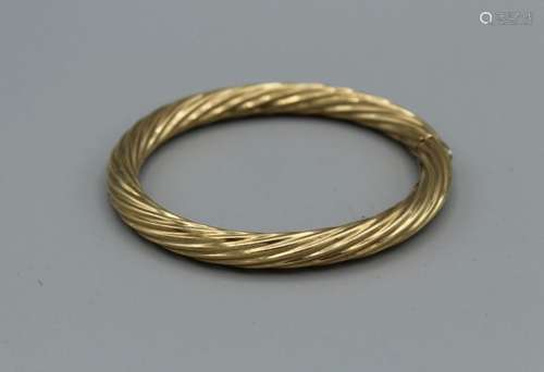 A hinged 9ct gold bangle in twisted form. Hinge and clasp in...