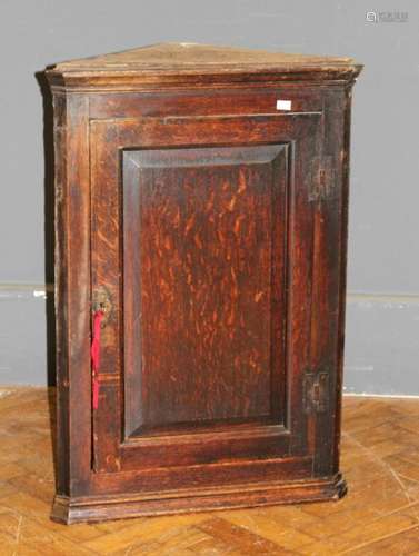 A George III oak wall mounting corner cupboard of small size...