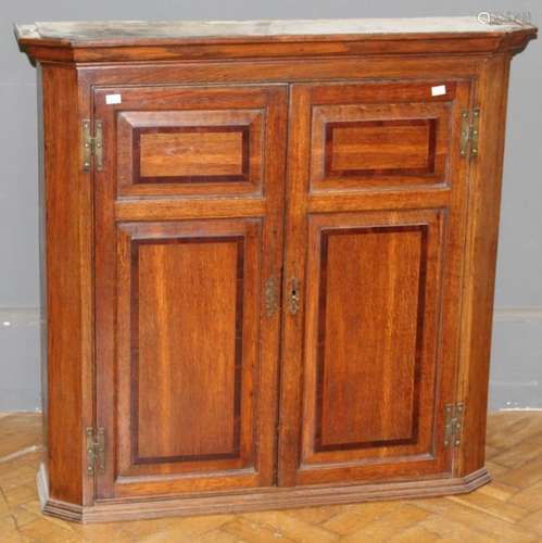 A 19th century oak wall cupboard, the moulded cornice over a...