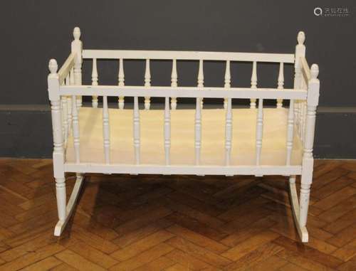 An Edwardian white painted rocking cradle with spindle turne...