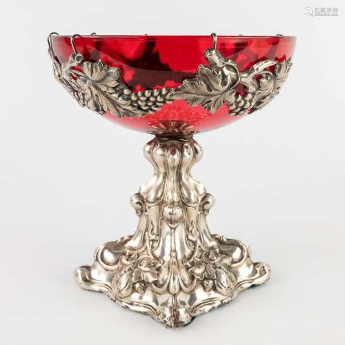 A red glass bowl on a silver base, decorated with grape vine...