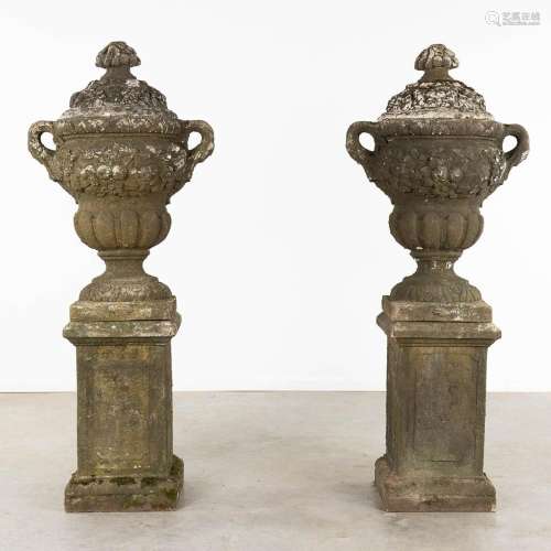 A pair of large urns with a lid, standing on a pedestal, con...