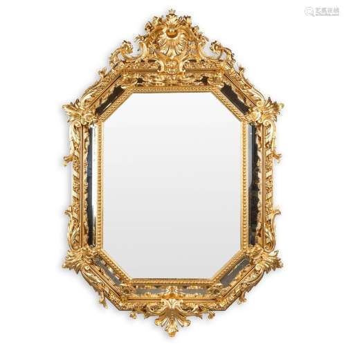 An antique mirror, sculptured gilt stucco and facetted glass...