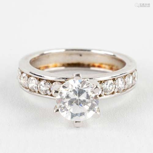 A ring with large solitaire and smaller stones/synthetic sto...