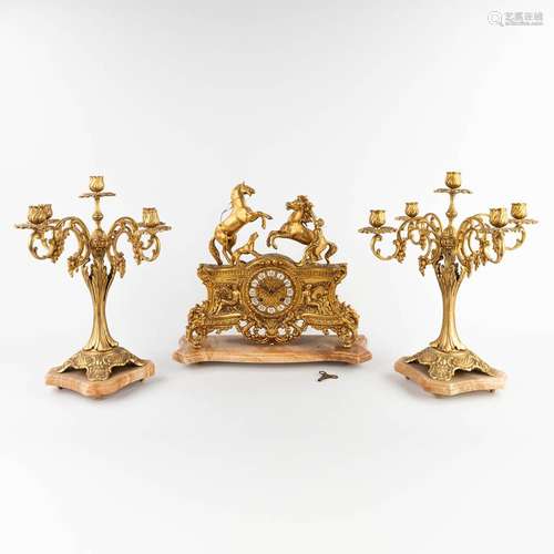 A three-piece mantle garniture clock and candelabra, polishe...