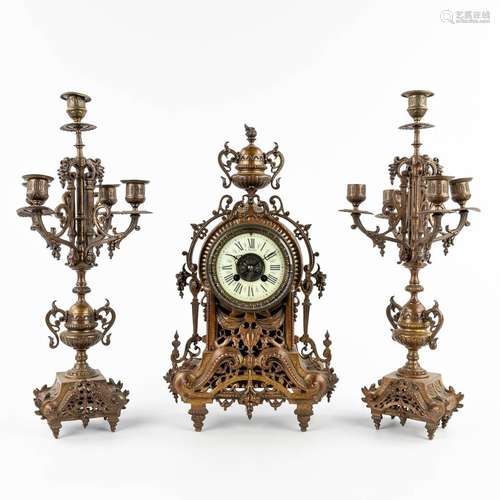 A three-piece mantle garniture clock and candelabra, patinat...