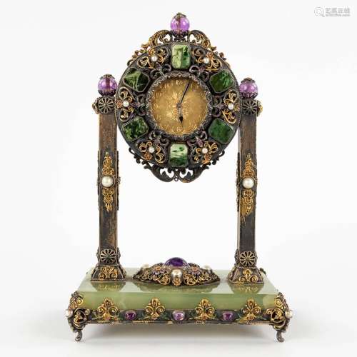 A mantle clock, silver and gold-plated metal and decorated w...