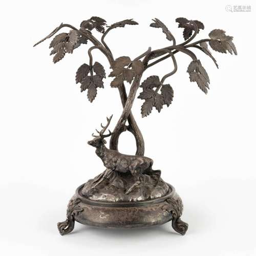 A figurine of a deer, walking under tall trees. Silver-plate...