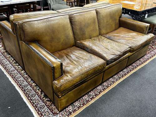 A pair of brown leather brass studded three seater settees, ...