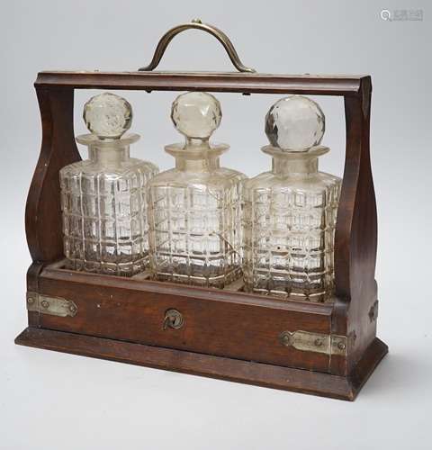 A three bottle oak and electroplate mounted tantalus, 36cms ...