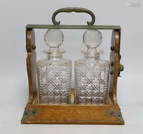 An Edwardian two bottle oak tantalus, 17cms wide